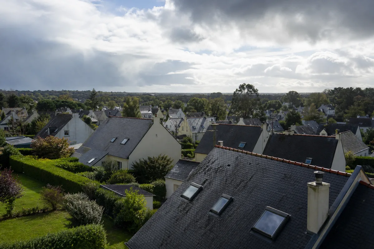 Toits en ardoise d’un quartier pavillonnaire breton sous un ciel d’ouest changeant