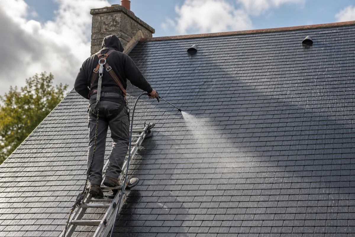 Application d’un traitement de protection sur une toiture ardoise, silhouette de couvreur de dos