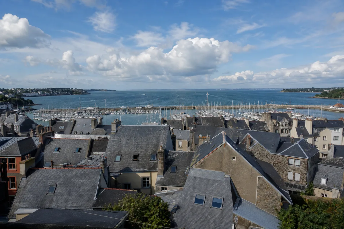 Panorama de toits d’ardoise d’une ville portuaire bretonne sous un ciel lumineux
